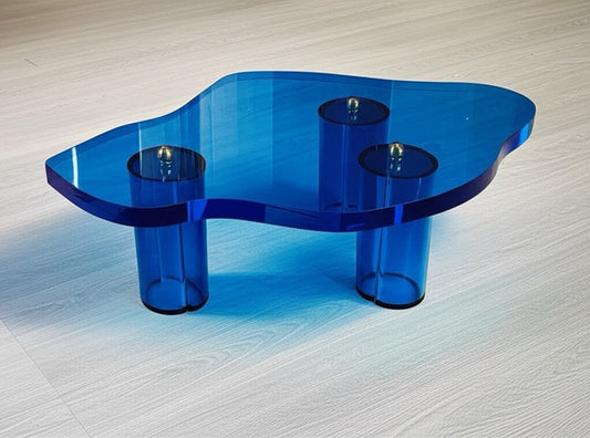 The Azure Brass Mirage, a stunning blue acrylic coffee table showcasing a sculptural design with elegant brass detailing.