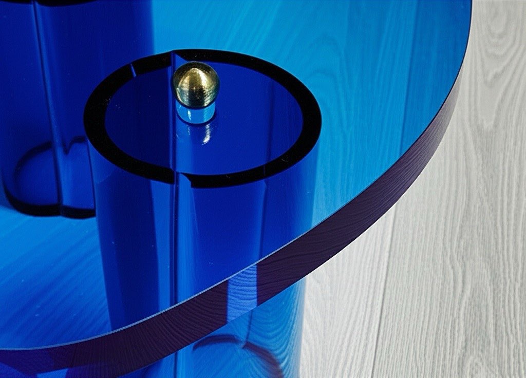 Close-up view of The Azure Brass Mirage blue acrylic coffee table highlighting its unique wave-like silhouette and high-quality brass accents.